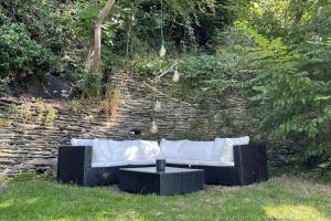 białą kanapę siedzącą w trawie obok kamiennej ściany w obiekcie Le Belle-Vue w La-Roche-en-Ardenne