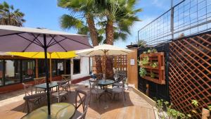 - deux tables et chaises avec parasols sur la terrasse dans l'établissement Hostel Willka Kuti Backpackers, à Arica