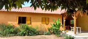 una casa con techo rojo y una silla delante en Sénégal CASAMANCE, en Boukot Ouolof