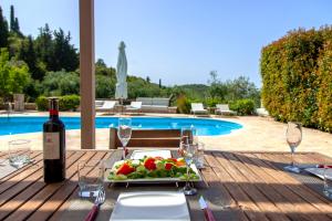 a table with a plate of fruit and a bottle of wine at SAZ VILLAS in Sivota
