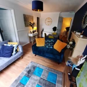 a living room with a blue couch and yellow pillows at Blenheim Way is a beautiful apartment in a quiet location yet minutes from major attractions and City centre Great for families Sleeps 6 in Birmingham