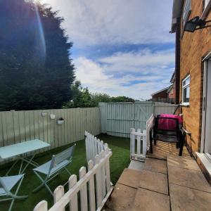 un patio trasero con una valla blanca, una mesa y sillas en Blenheim Way is a beautiful apartment in a quiet location yet minutes from major attractions and City centre Great for families Sleeps 6 en Birmingham