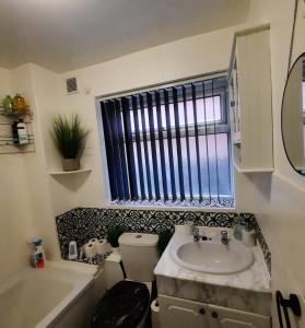 baño con lavabo y aseo y ventana en Blenheim Way is a beautiful apartment in a quiet location yet minutes from major attractions and City centre Great for families Sleeps 6 en Birmingham