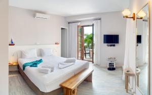 Dormitorio blanco con cama grande y banco de madera en Villa Rossa en Parga