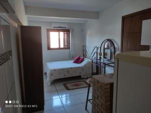 um quarto com uma cama com uma almofada cor-de-rosa em Kitnet da Fô em Pelotas