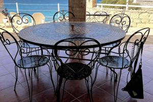 a black table and chairs with a table and the ocean at Villa GÊMEO vue mer, piscine accès privé plage in Calheta Do Maio