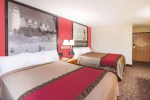 duas camas num quarto de hotel com paredes vermelhas em Super 8 by Wyndham West Branch em West Branch