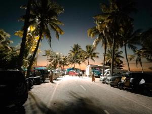 a street with palm trees and cars parked on a beach at Ethus'villahomestay in Mararikulam +7 photos