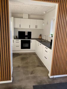 uma cozinha com armários brancos e electrodomésticos pretos em Hytten em Lemvig
