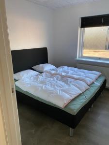 1 cama no hecha en una habitación con ventana en Hytten, en Lemvig