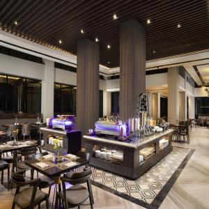 un restaurant avec des tables et des chaises et un buffet dans l'établissement Hotel Santika Premiere Padang, à Padang