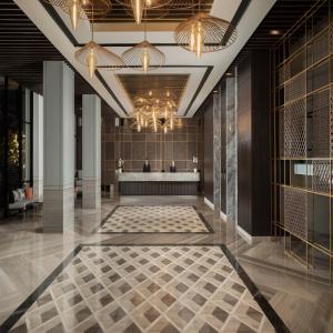 a lobby of a hotel with a tile floor and chandeliers at Hotel Santika Premiere Padang in Padang