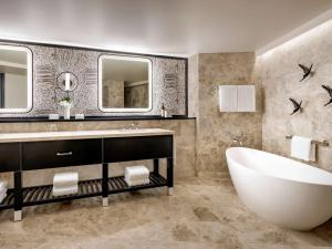 La salle de bains est pourvue d'une baignoire, d'un lavabo et de miroirs. dans l'établissement Fairmont Kea Lani, Maui, à Wailea