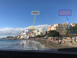 a beach with people in the water and buildings at Medano Seaview Penthouse CASA CORINA III in El Médano