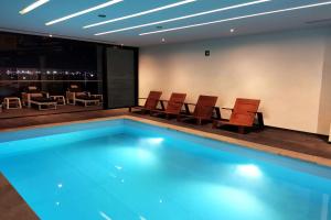 a swimming pool in a room with chairs and a table at Ramada Encore by Wyndham Guadalajara Aeropuerto in Guadalajara