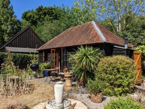 a small house with a roof in a garden at Cabin in the Forest in Brockenhurst