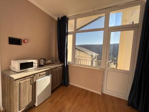 a kitchen with a microwave and a large window at Ahval Hotel in Qusar