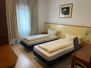 a hotel room with two beds and a desk at Hotel Zum Klüverbaum in Bremen