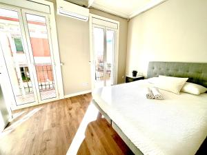 sypialnia z dużym białym łóżkiem i dużymi oknami w obiekcie Sunny apartment Gracia - Joanic Renovated w Barcelonie
