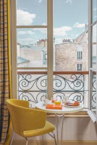 a table and two chairs in front of a window at Hotel Le petit Paris in Paris