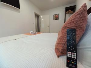 un mando a distancia sentado sobre una cama en Ares do Mar - 4 beds apartment and car parking, en Matosinhos