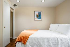 Un dormitorio con una cama blanca con una manta naranja. en *2bdr Victorian Home away from Home - *Central Loc en Sacramento