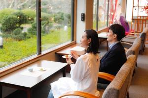 Un uomo e una donna seduti a un tavolo in un ristorante di たまご肌美人の湯　美榛苑 a Uda