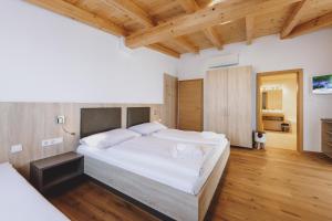 sypialnia z dużym białym łóżkiem i drewnianą podłogą w obiekcie Appartements Sulzer by we rent, SUMMERCARD INCLUDED w mieście Zell am See