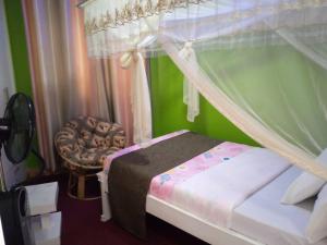 1 dormitorio con 1 cama con dosel y 1 silla en Bethel Resort & Hotels en Gulu