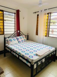 Cama grande en habitación con ventanas en Mikocheni Home stay en Dar es Salaam