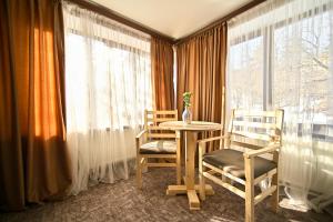 uma mesa e duas cadeiras num quarto com janelas em Kompozitor Hotel Dilijan em Dilijan
