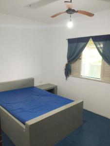 um quarto com uma cama, uma ventoinha de tecto e uma janela em Casa frente para o mar em Nova Viçosa