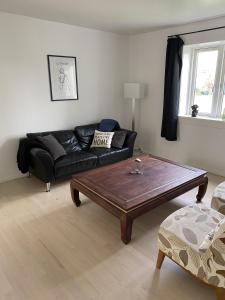 uma sala de estar com um sofá preto e uma mesa de centro em Hus m gaard have, 25m fra havet, havn, Strand, High speet internet, restauranter em Rungsted