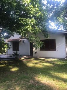 a white house with a tree in front of it at Puerto Paraíso in Sierra de los Padres +17 photos