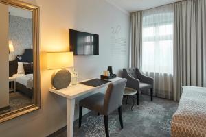 a hotel room with a desk and a bed and a mirror at Hotel Via Regia - VIAs-Hotels in Görlitz
