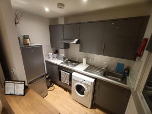 Lovely 1 bedroom apartment in London في لندن: مطبخ صغير مع غسالة ومغسلة