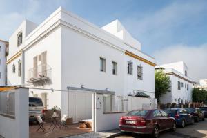 una casa blanca con un coche rojo estacionado en un estacionamiento en Magno Apartments Robles with Bath Tub and Private Parking en Sevilla