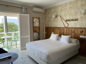 Un dormitorio con una gran cama blanca y una ventana en Alameda Hostal Boutique, en Tarifa