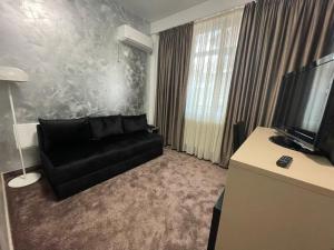 ein Wohnzimmer mit schwarzem Sofa und Fernseher in der Unterkunft Hotel Rivoli in Bukarest