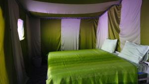 een slaapkamer met een groen bed in een tent bij Camp Sahara Majestic in Mhamid