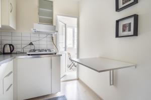 eine weiße Küche mit einer Theke und einem Tisch in der Unterkunft Modern Flat with Balcony on Bagdat Street in Istanbul