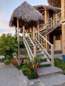 a staircase leading to a building with a thatch roof at Pousada Nascer da Lua in Fortim