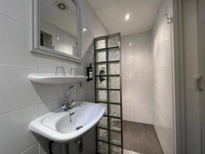 a white bathroom with a sink and a mirror at Hotel Heerlijkheid Bergen in Bergen