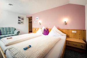 a hotel room with two beds and a chair at Pension der Steinbock - das 300 Jahre alte Bauernhaus - TIROL in Sankt Anton am Arlberg