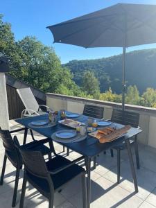 une table bleue et des chaises sur un balcon avec un parasol dans l'établissement Les 3 Frères : plain-pied en pleine nature, à Vresse-sur-Semois
