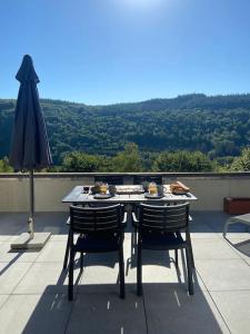 einen Tisch und Stühle auf einem Balkon mit Sonnenschirm in der Unterkunft Les 3 Frères : plain-pied en pleine nature in Vresse-sur-Semois