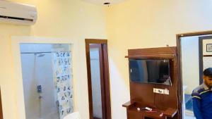 a man standing in a room with a television at The Miraj Hotel in Murthal