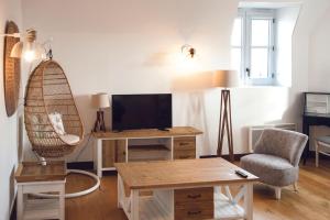 uma sala de estar com uma televisão, uma cadeira e uma mesa em Résidence de l'Arsenal Royal - Meublés de Tourisme em Rochefort