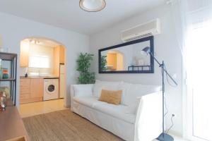 un divano bianco in soggiorno con specchio di Budget Beach Studio 22 a Sant Antoni de Calonge