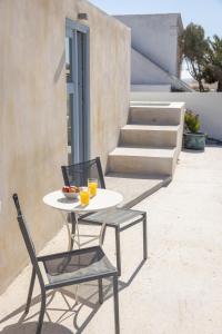 stół z 2 krzesłami i 2 kieliszki soku pomarańczowego w obiekcie Oia's Cellars w mieście Oia